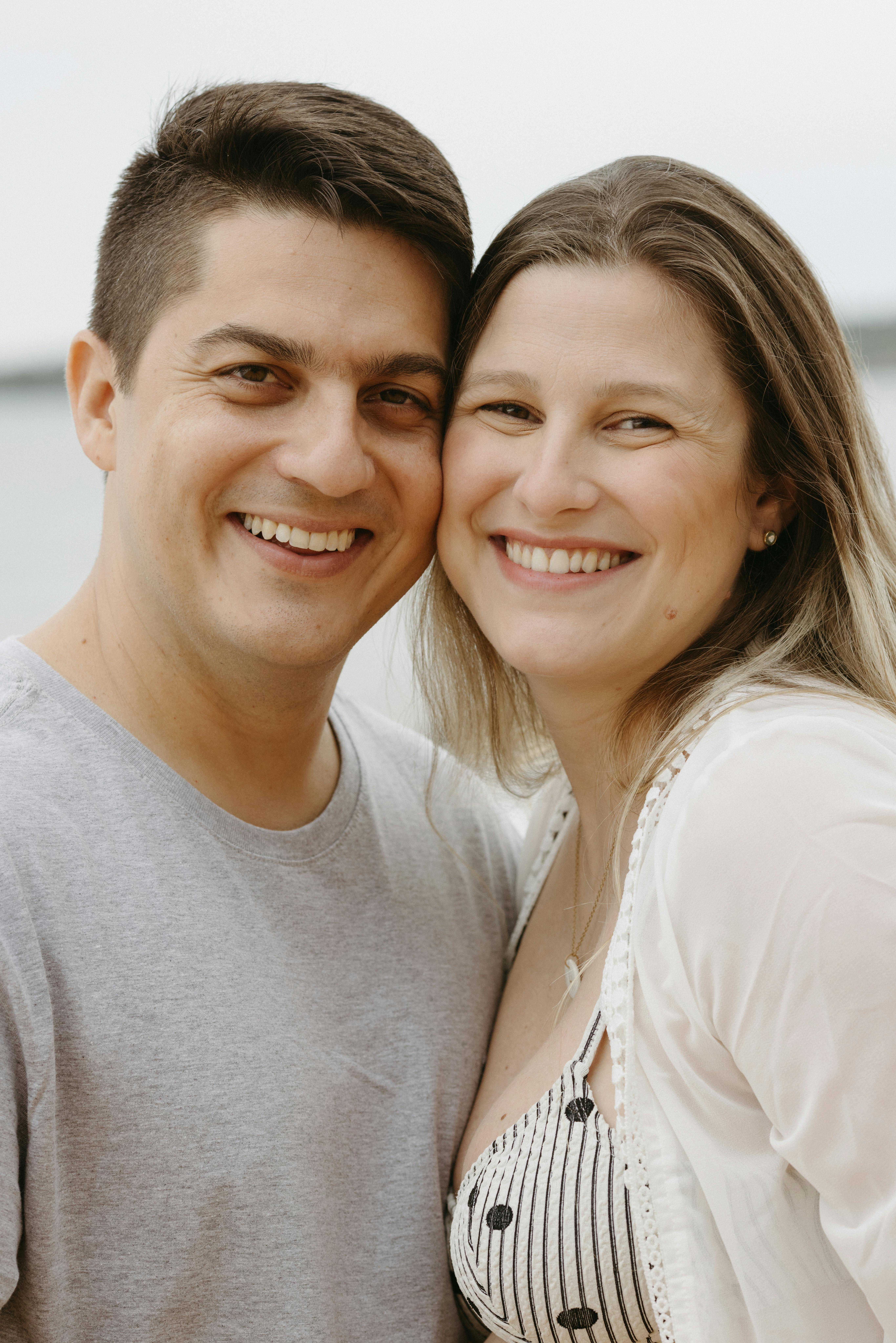 A joyful couple smiling warmly while outdoors during a summer day.