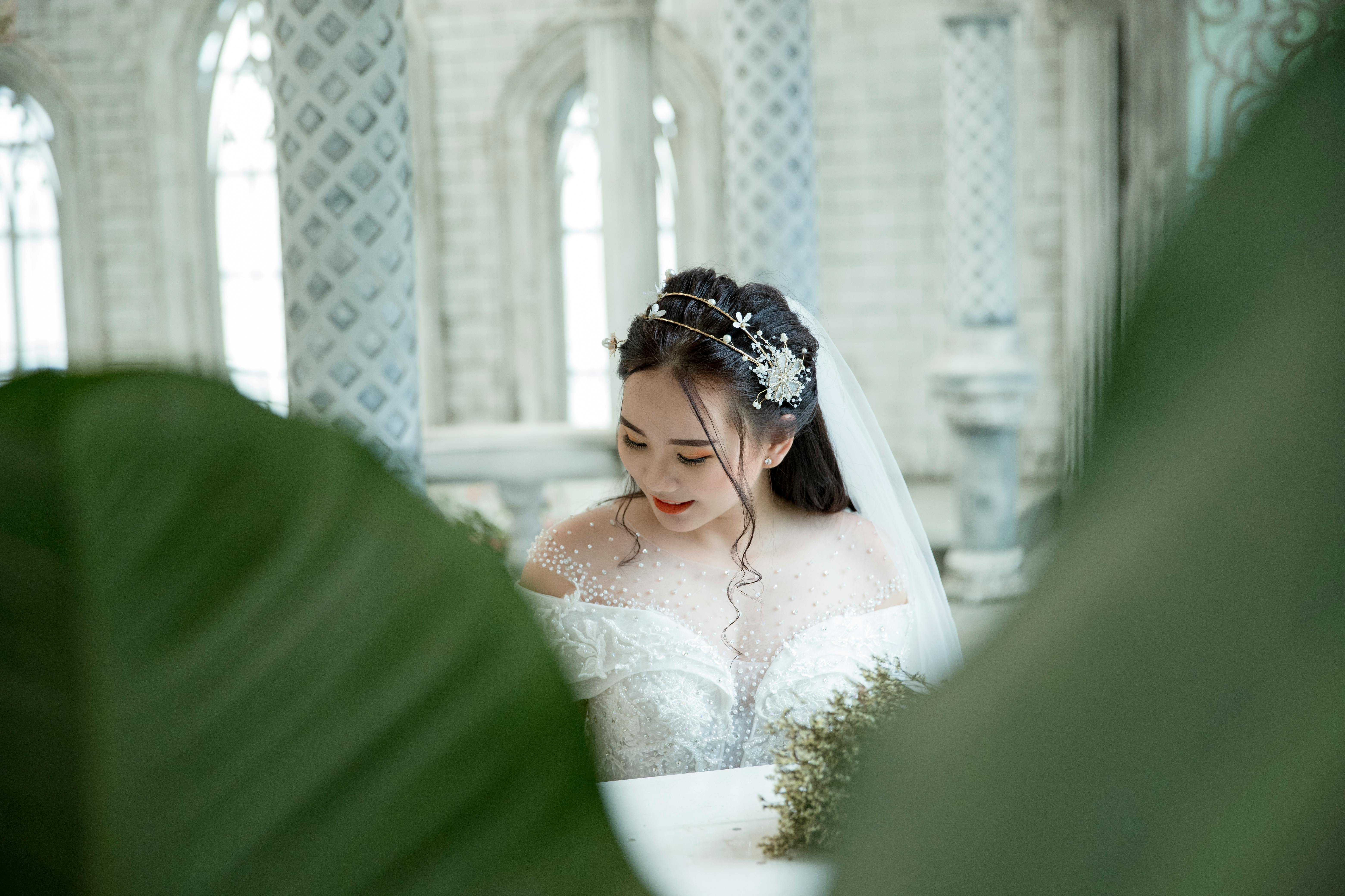 Beautiful bride in an elegant white wedding gown in a serene indoor setting.