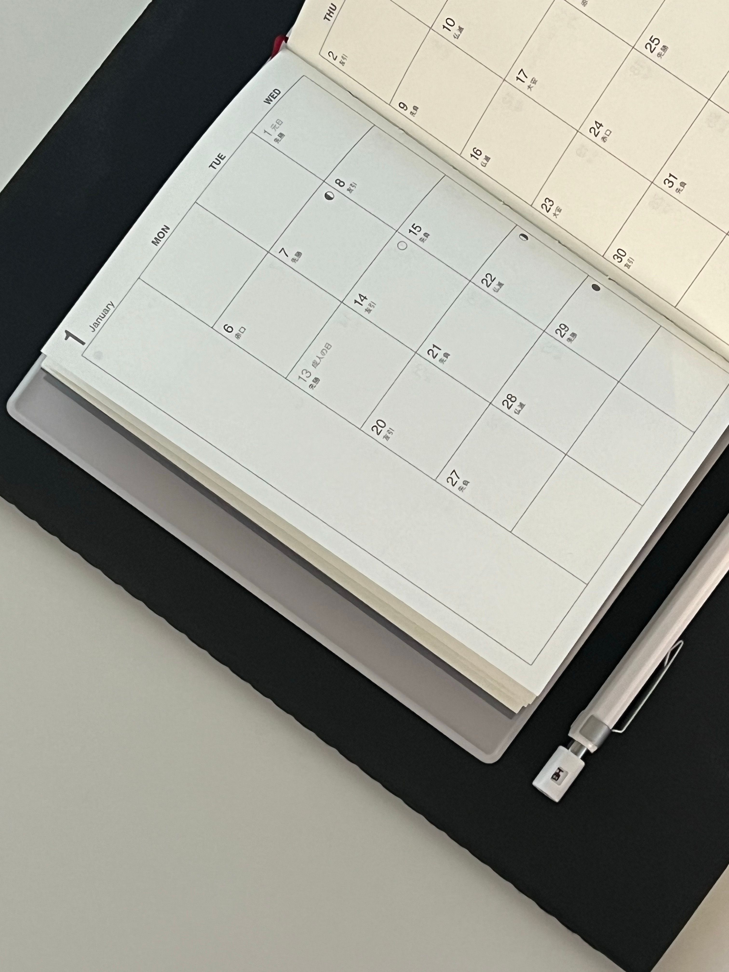 Minimalist desk with a paper planner, pen and calculator