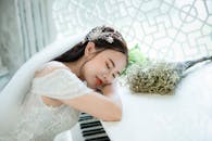 一位身着白色礼服的新娘，在室内的钢琴旁静静休憩，尽显优雅与宁静