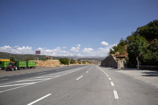 A quiet rural road under clear skies in Bingöl, Türkiye, with a truck parked on the side.