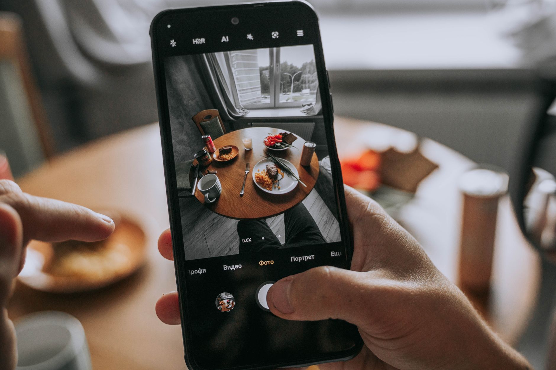 Smartphone captures a well-dressed table with food, showcasing modern dining indoors.