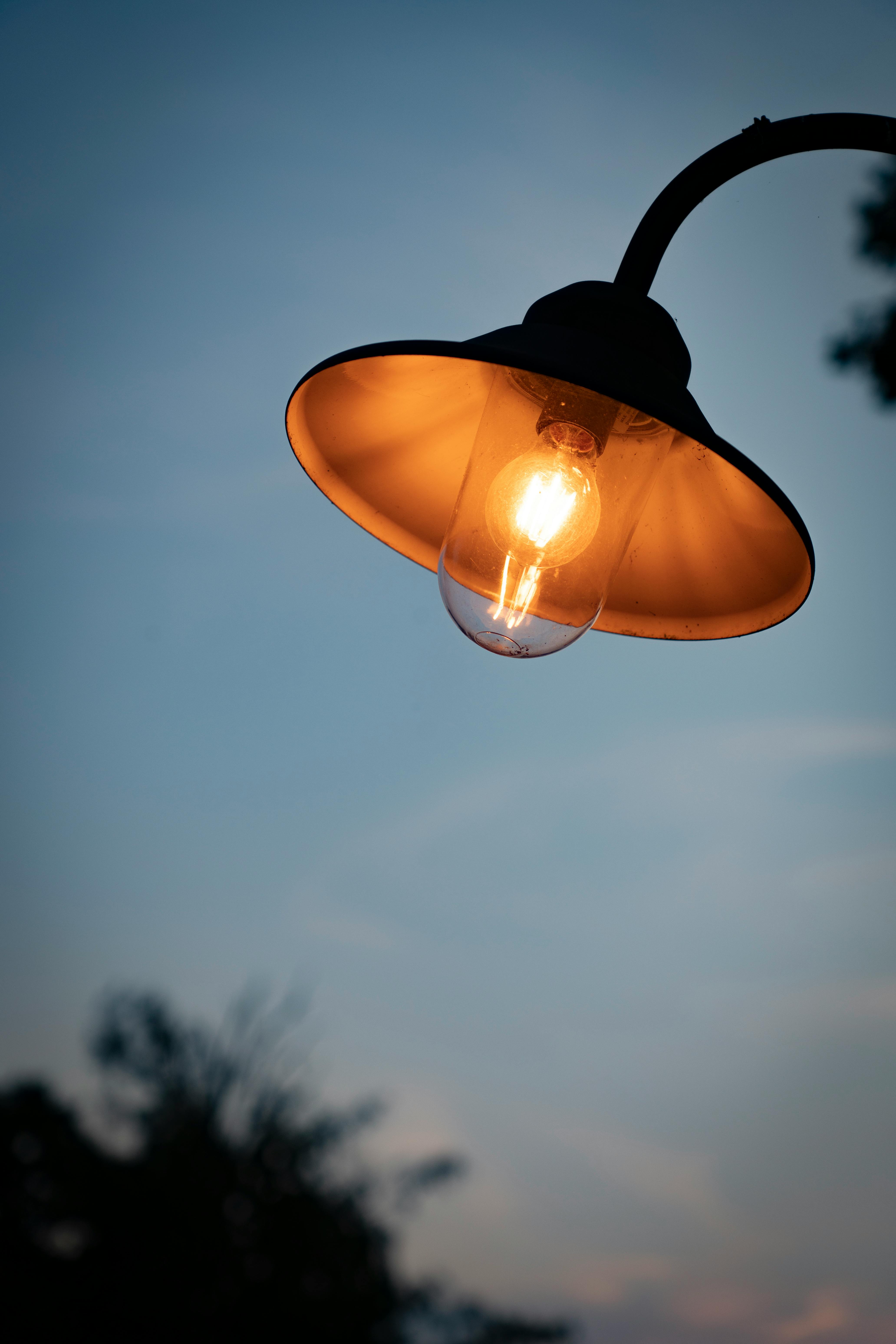 Close-up of a vintage outdoor lamp glowing against a twilight sky, creating a warm ambiance.