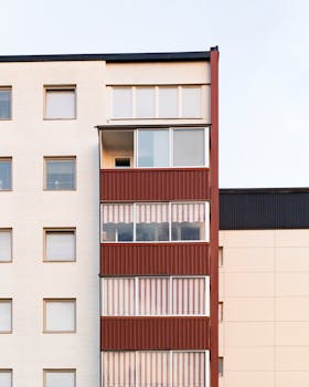 Capture of a modern residential building showcasing distinct red balconies against a neutral facade.