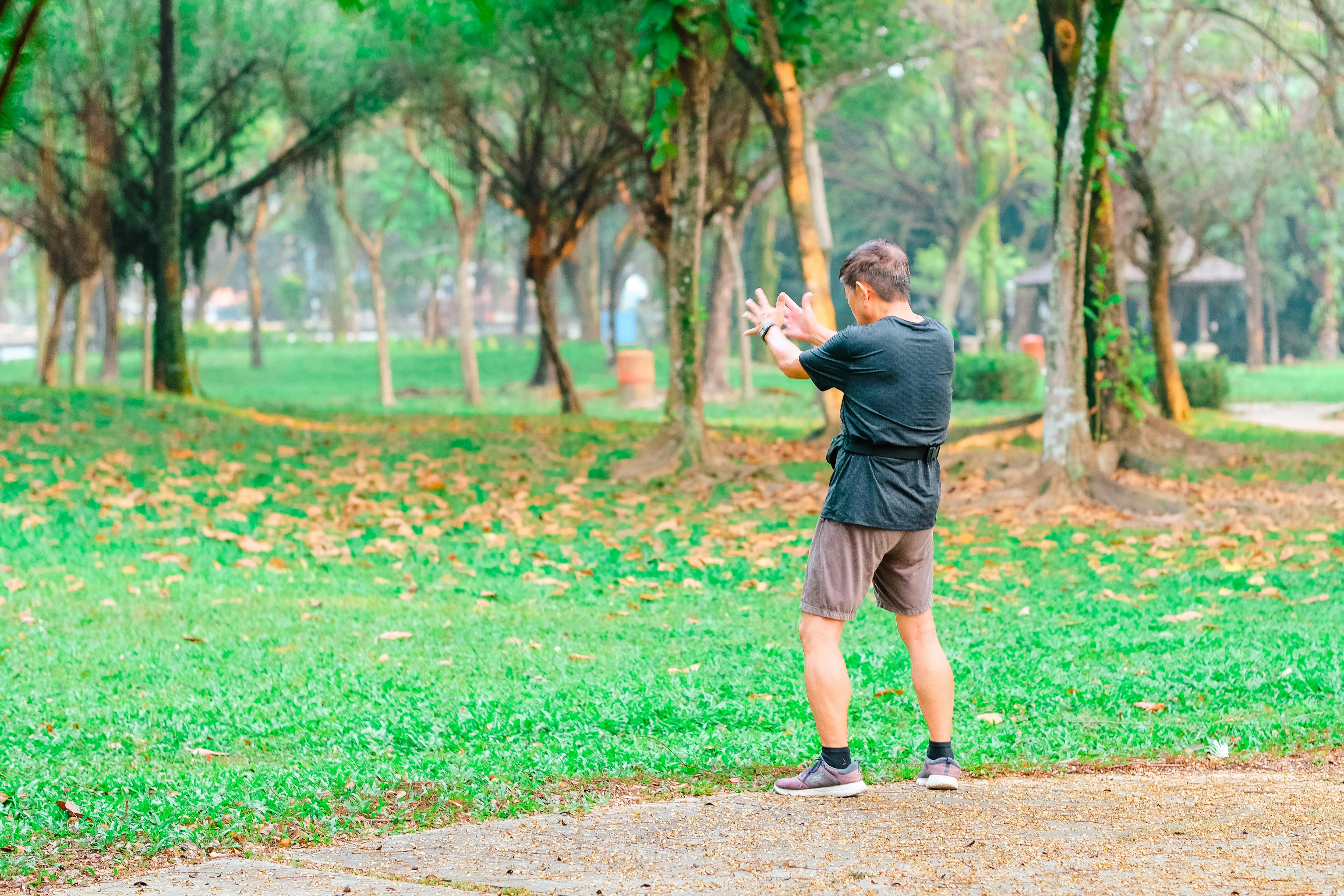 Group practicing tai chi in a park - mind body pain therapy
