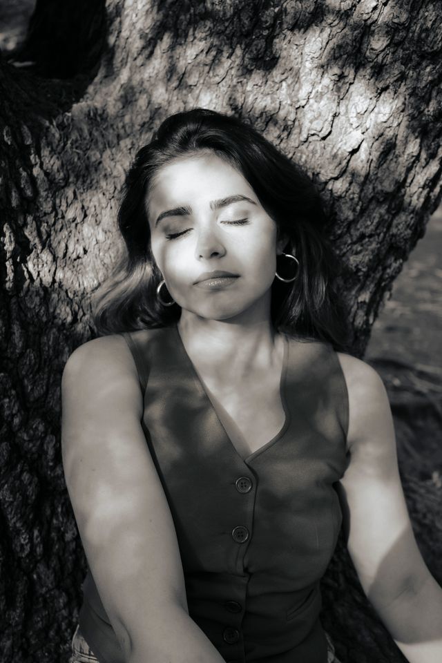 A woman resting against a tree trunk — photo by Hatice Baran on Pexels