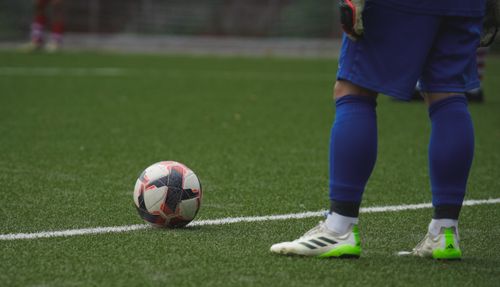 Free Close-up of a football player standing by a ball during a game on a grass pitch. Stock Photo