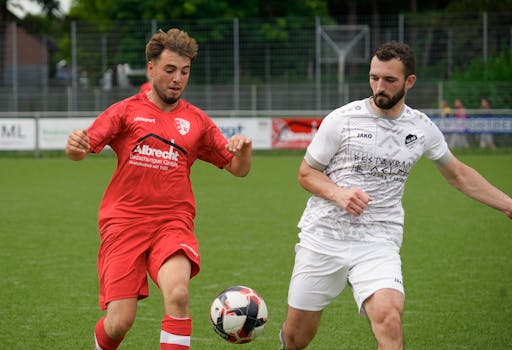 Two soccer players competing for the ball during a match on a grass field.
