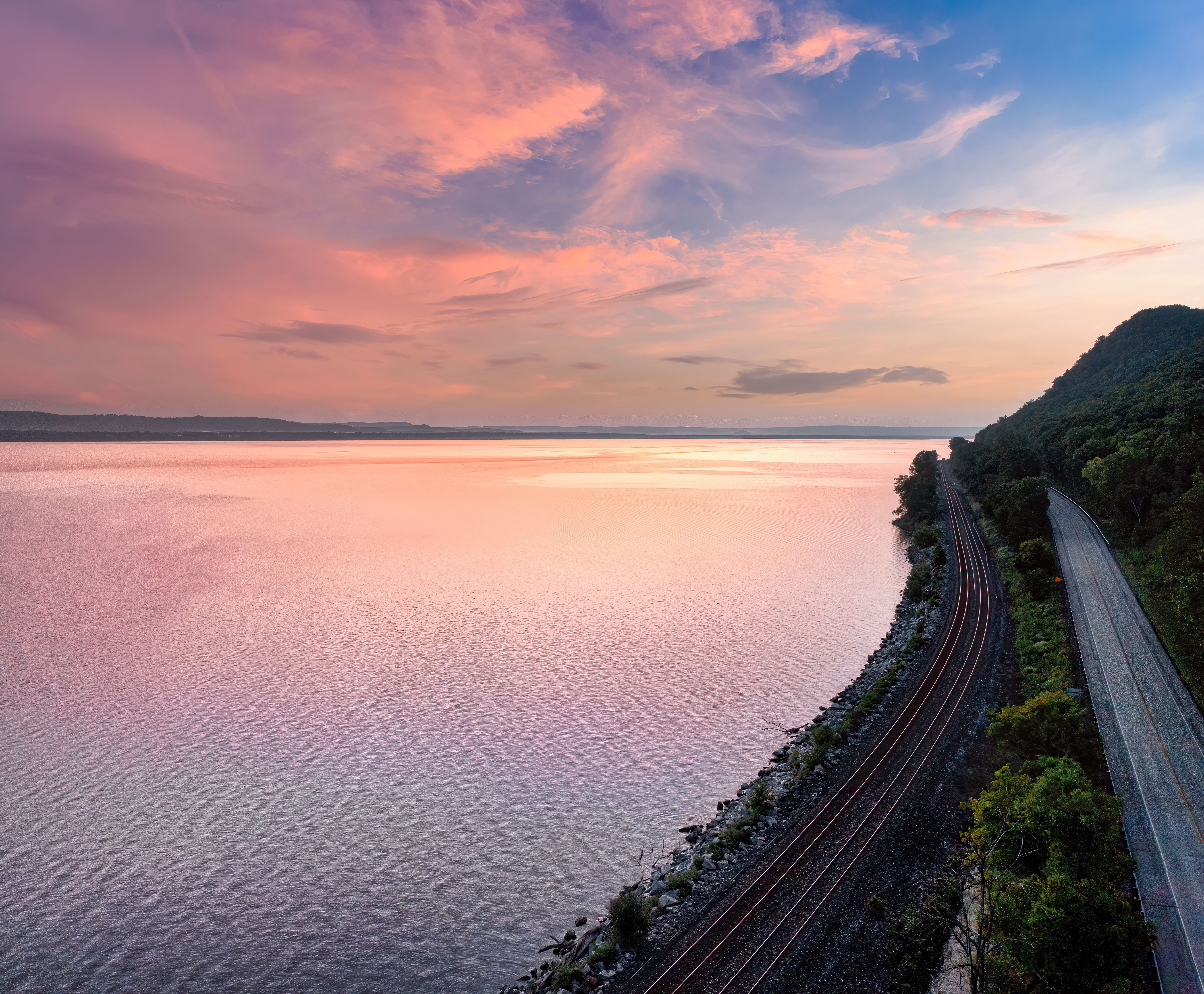 Beautiful sunset view over a lake with railroad tracks and road in Maple Springs, MN.