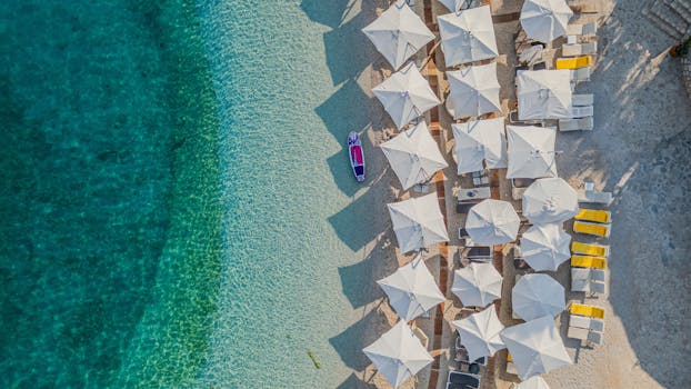 A stunning aerial view of a luxurious beach with umbrellas and crystal-clear water.