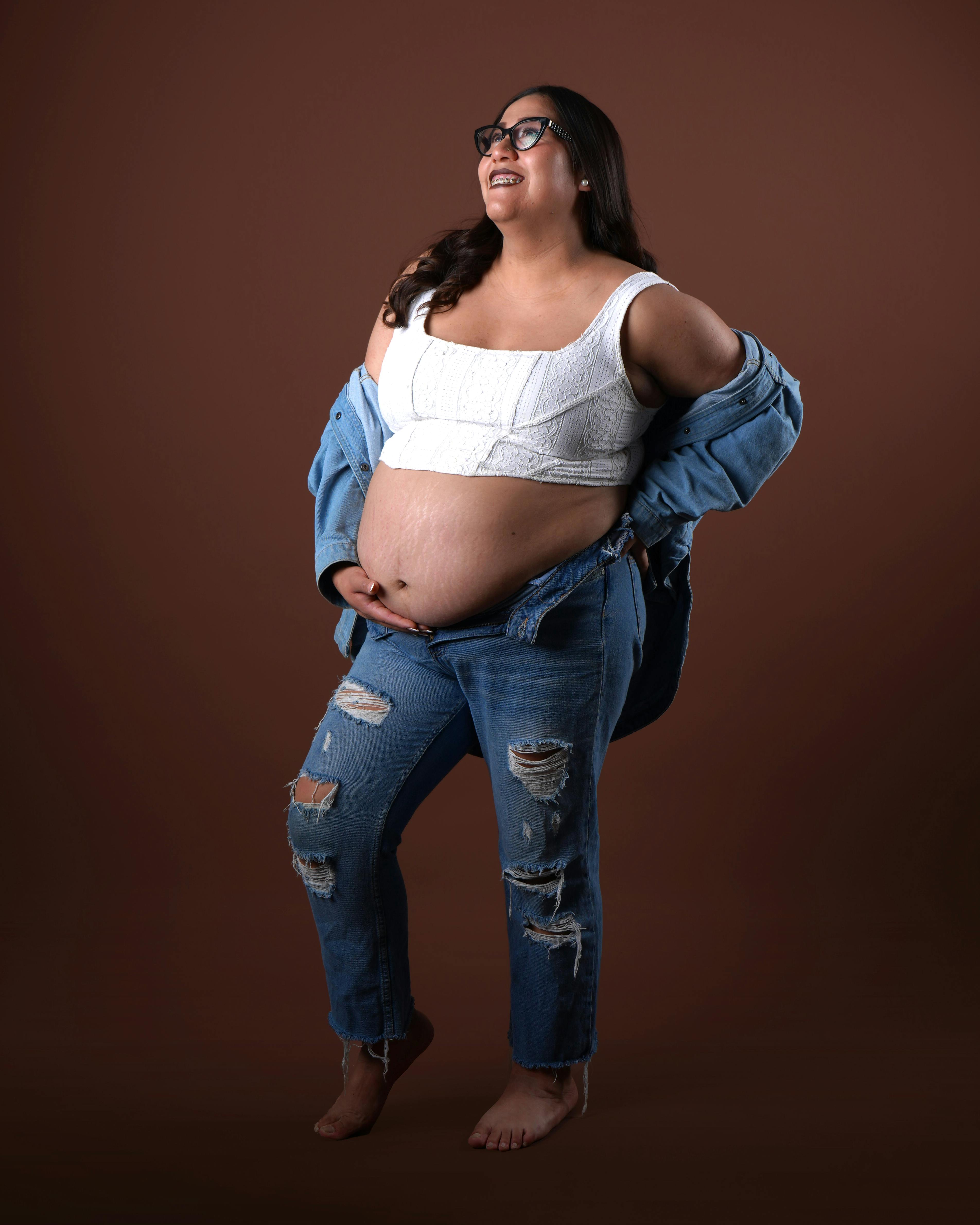 a pregnant woman in jeans and a white shirt