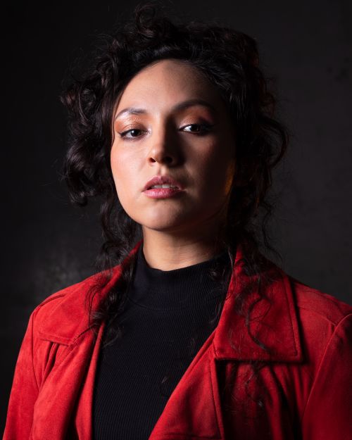 Free Studio portrait of a woman wearing a red jacket and black sweater, showcasing her confident expression. Stock Photo