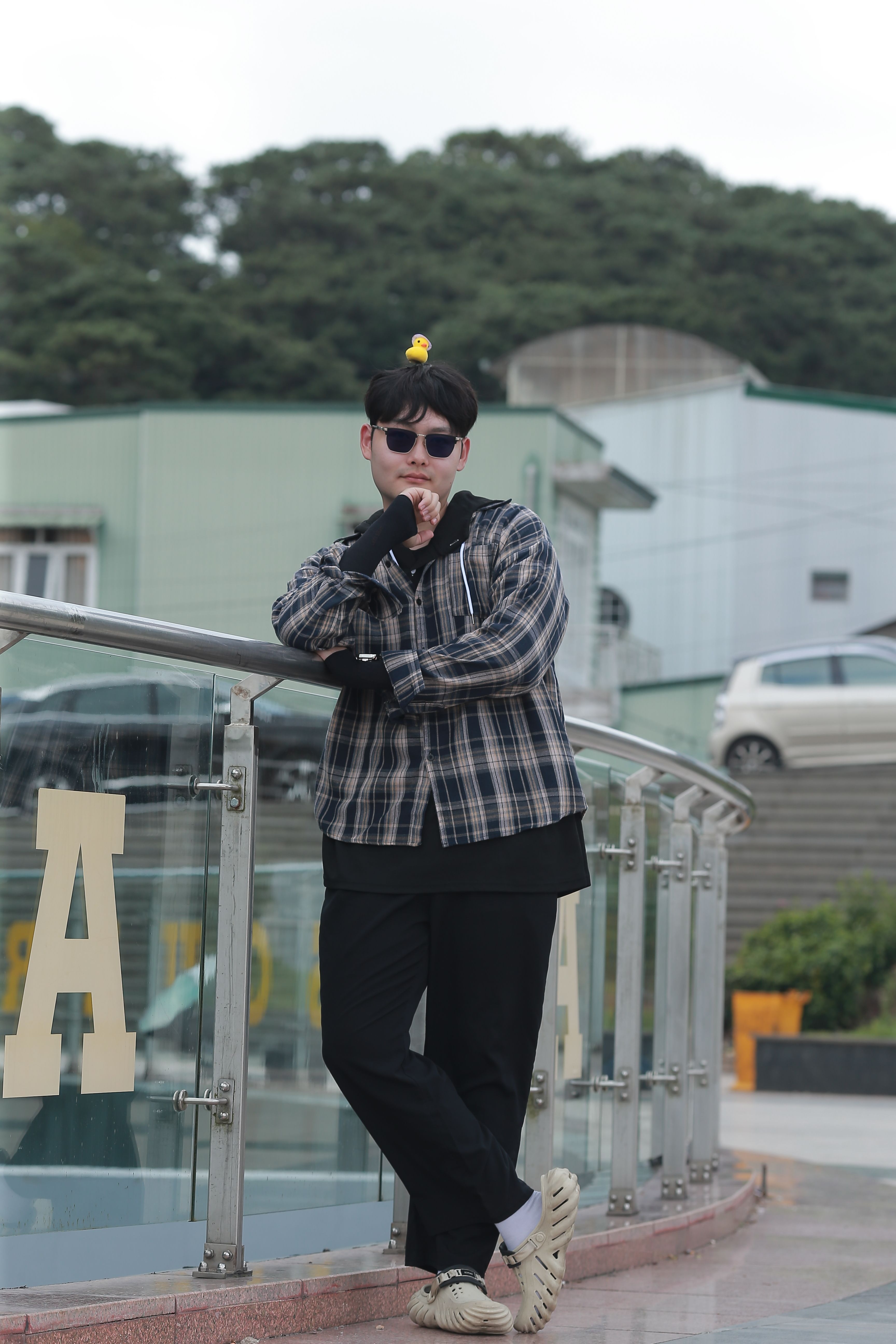 a man in sunglasses and a plaid shirt standing on a railing