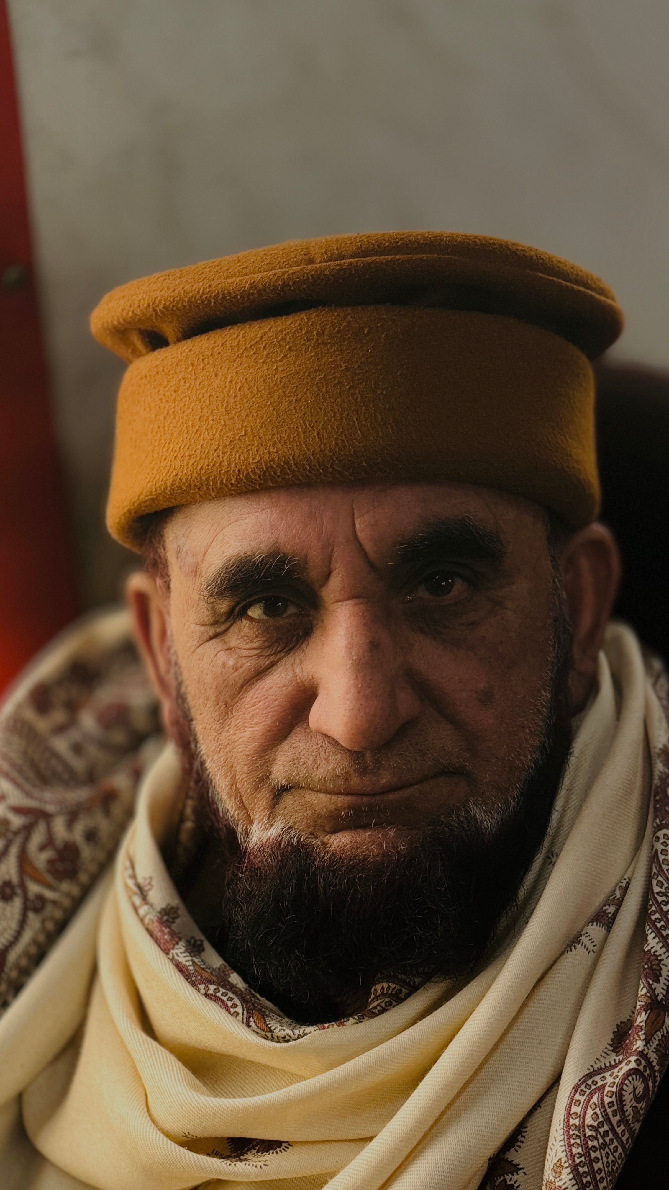 Close-up portrait of a senior man wearing a traditional cap and scarf, conveying wisdom and heritage.