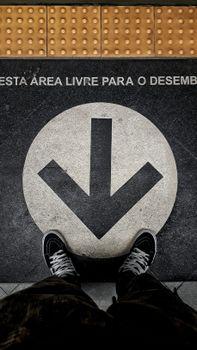 Close-up of a pavement arrow and sneakers indicating direction in a metro area.
