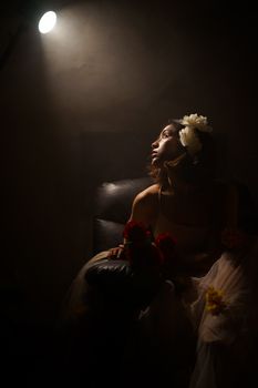 Artistic portrait of a woman in dark lighting, holding flowers, with a dramatic spotlight.. pexels, artistic, portrait