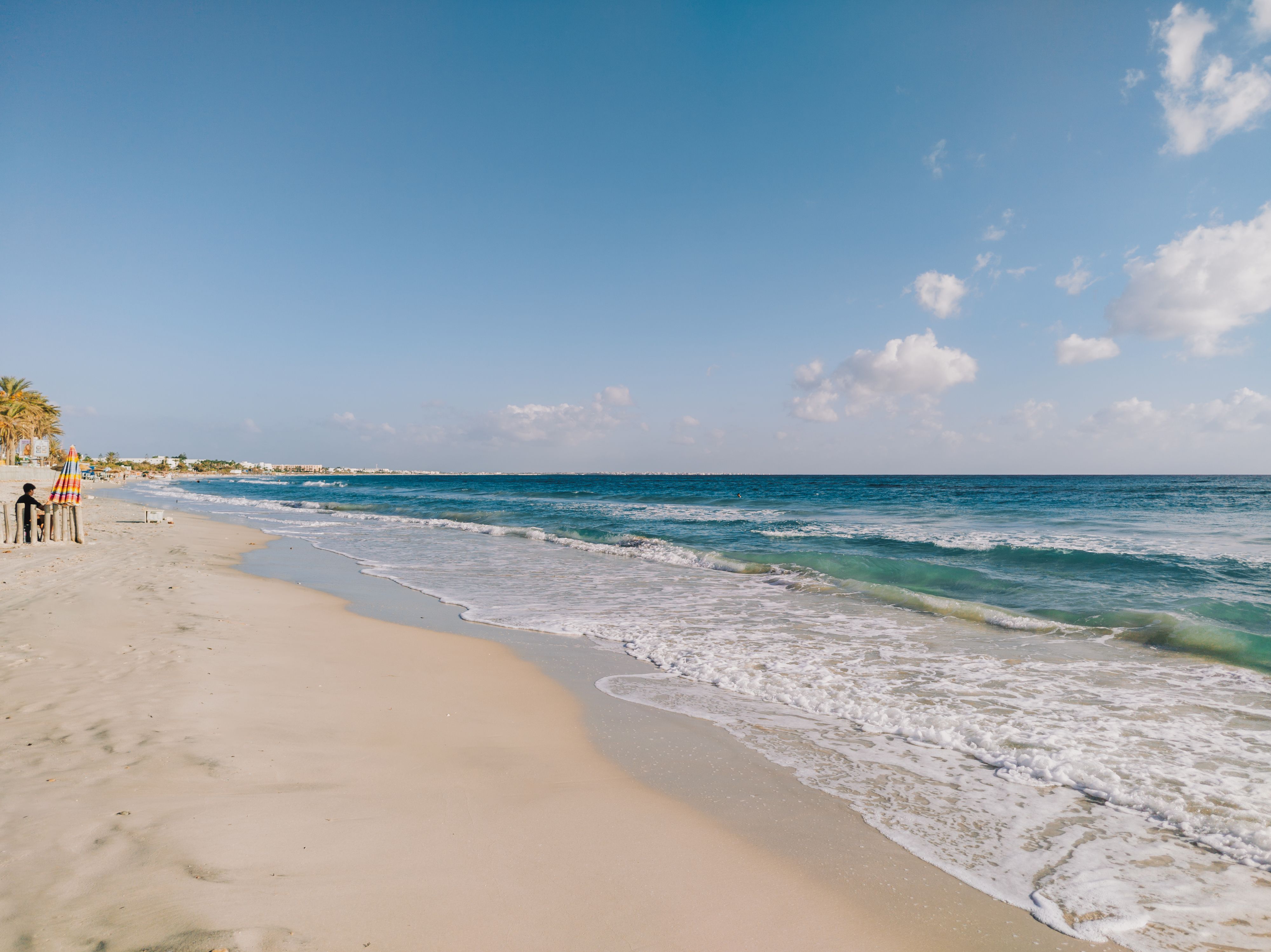 Sunny Beach with Glistening Waves and Clear Skies · Free Stock Photo