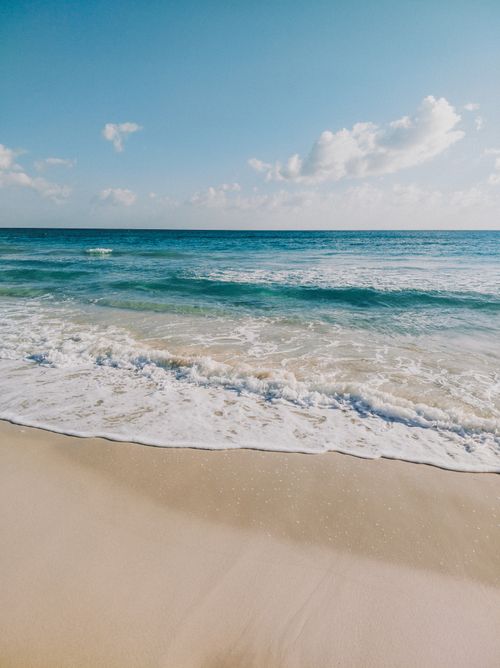 Free Peaceful beach scene with gentle waves and clear sky, capturing the tranquility of the ocean. Stock Photo