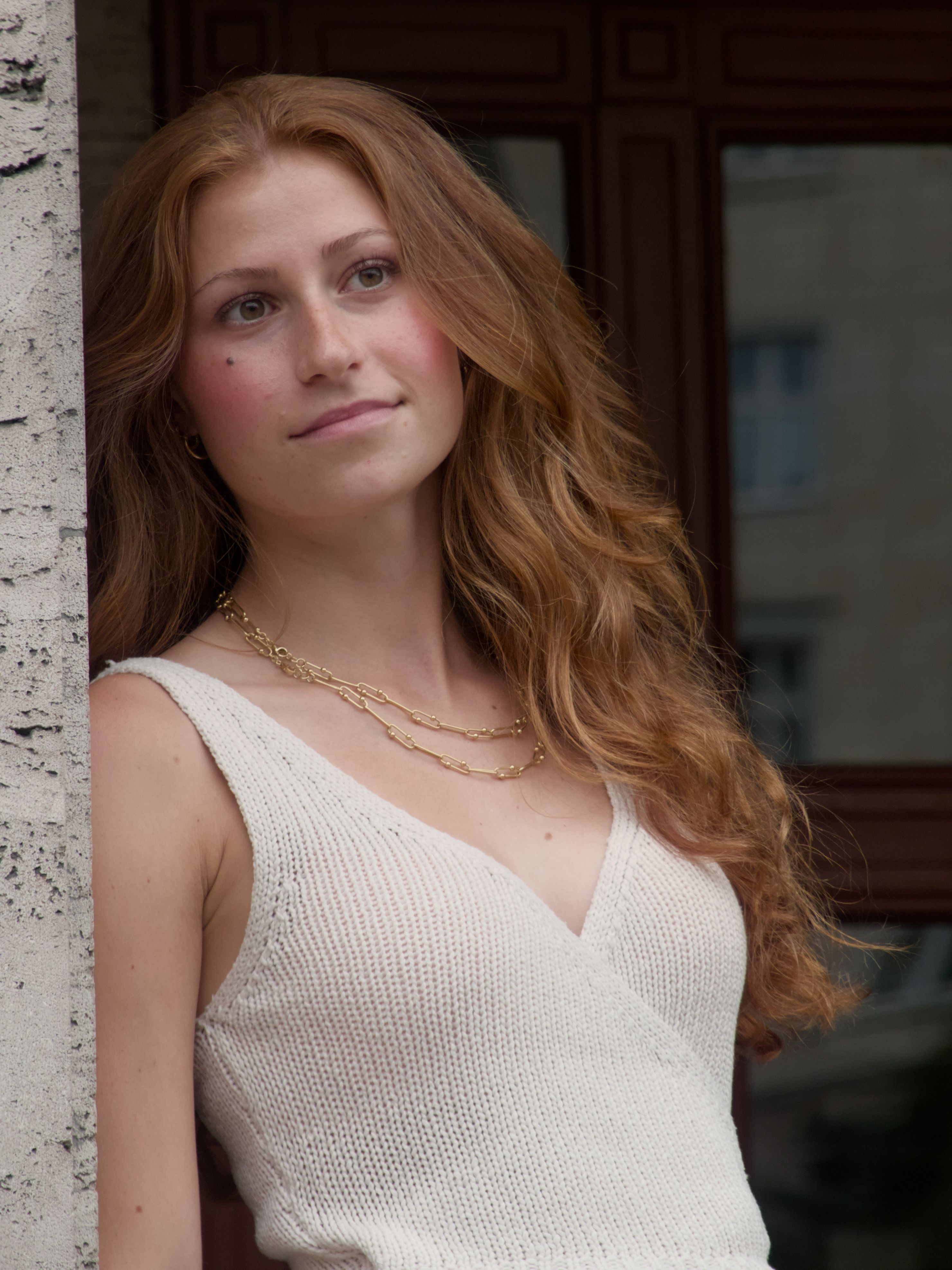 Portrait of a young woman with long hair and jewelry, standing outdoors in Berlin.