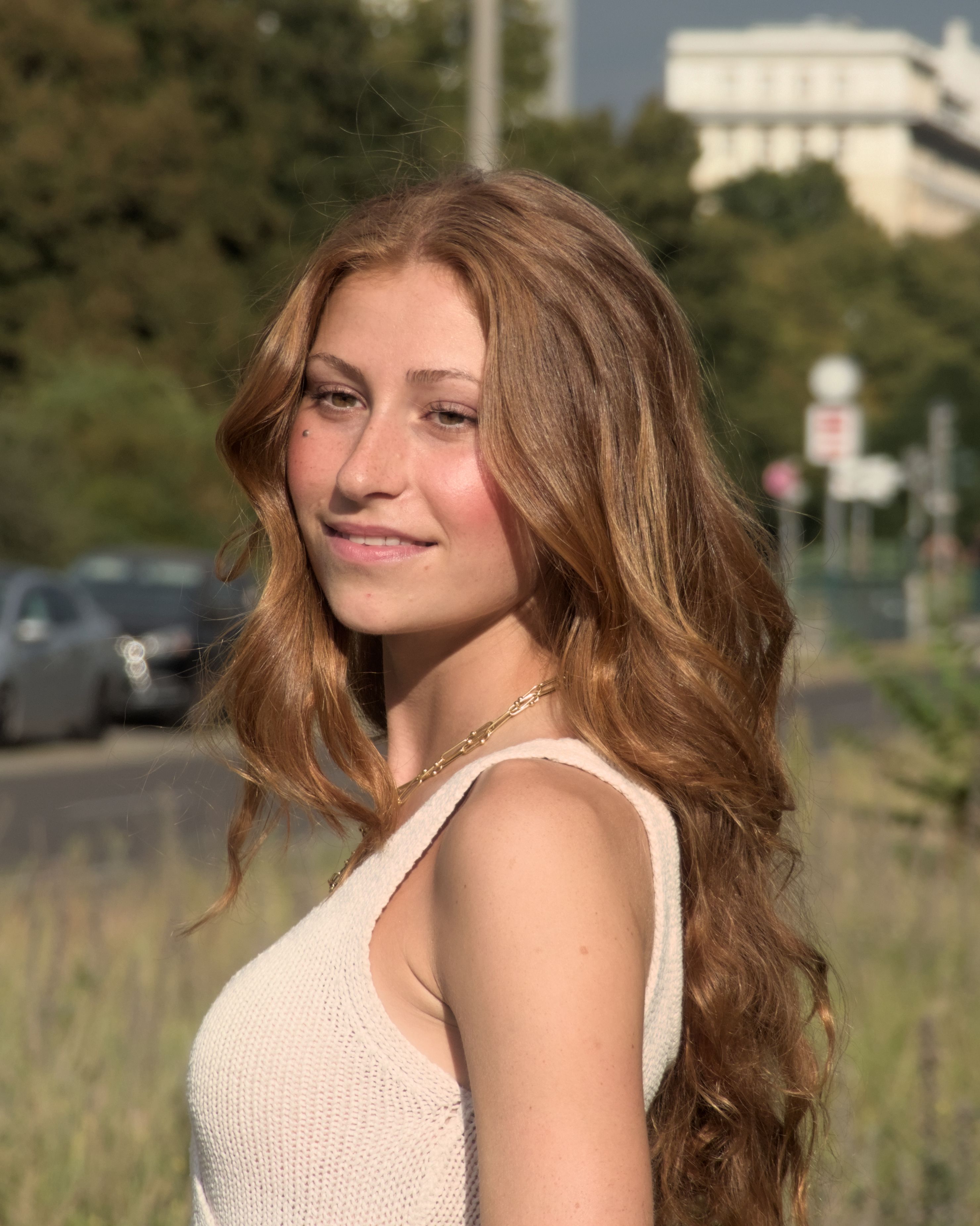 A young woman with red hair smiling outdoors in Berlin. Bright and casual.