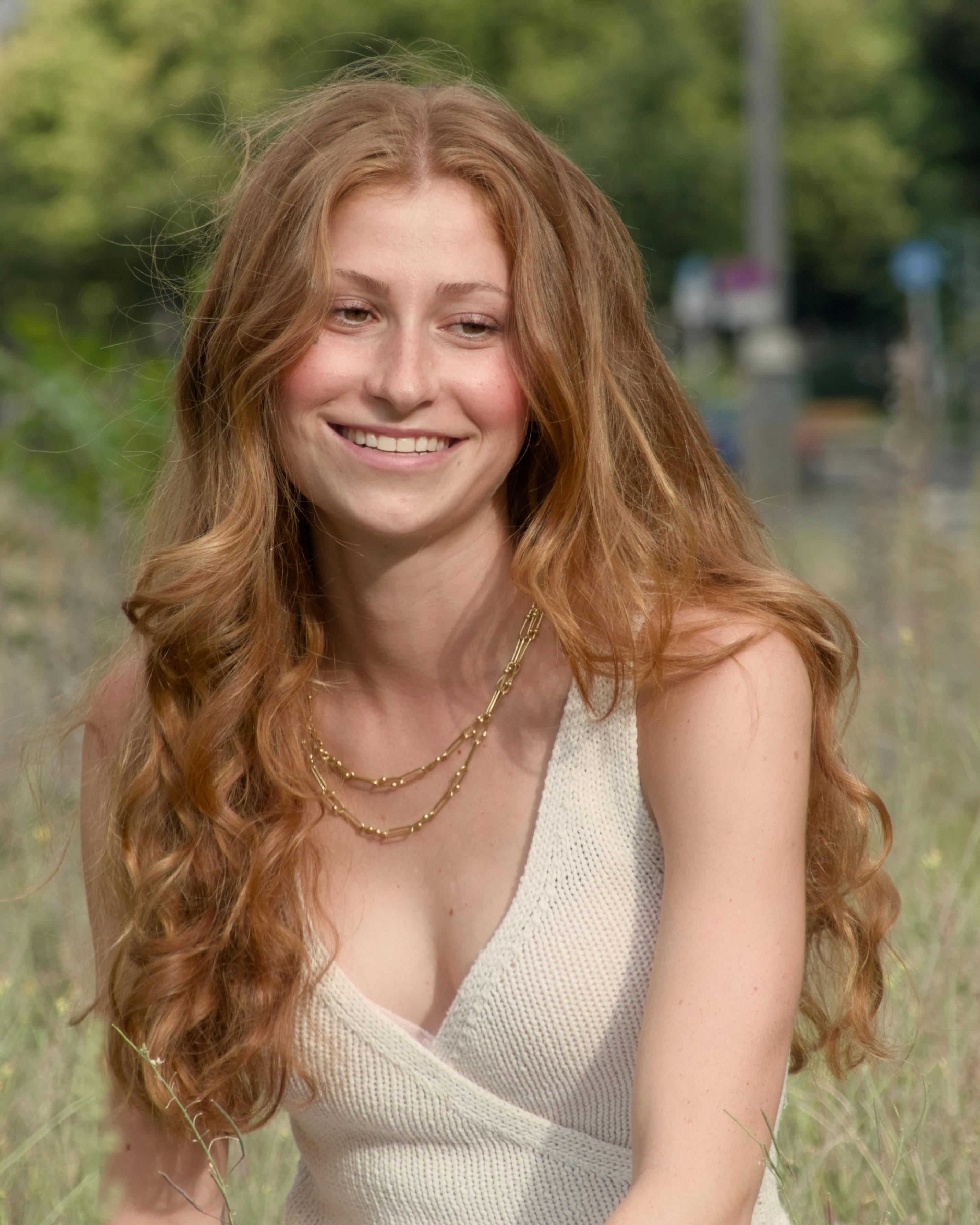 a woman with long red hair is sitting in a field