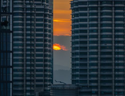 Free A stunning sunset framed between the iconic Petronas Twin Towers in Kuala Lumpur, Malaysia. Stock Photo