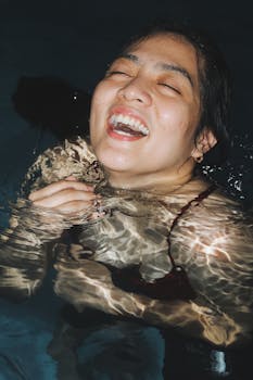 Close-up of a smiling woman enjoying night swimming, capturing joyful and carefree moments.