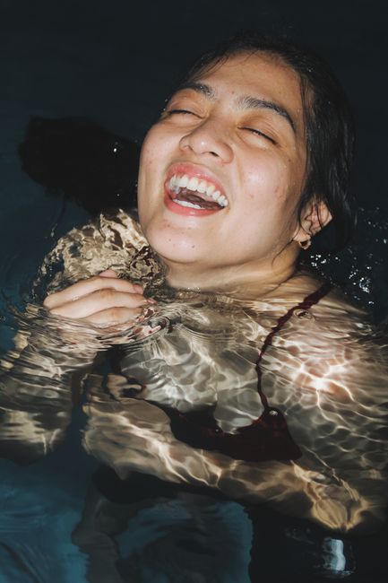 Close-up of a smiling woman enjoying night swimming, capturing joyful and carefree moments.