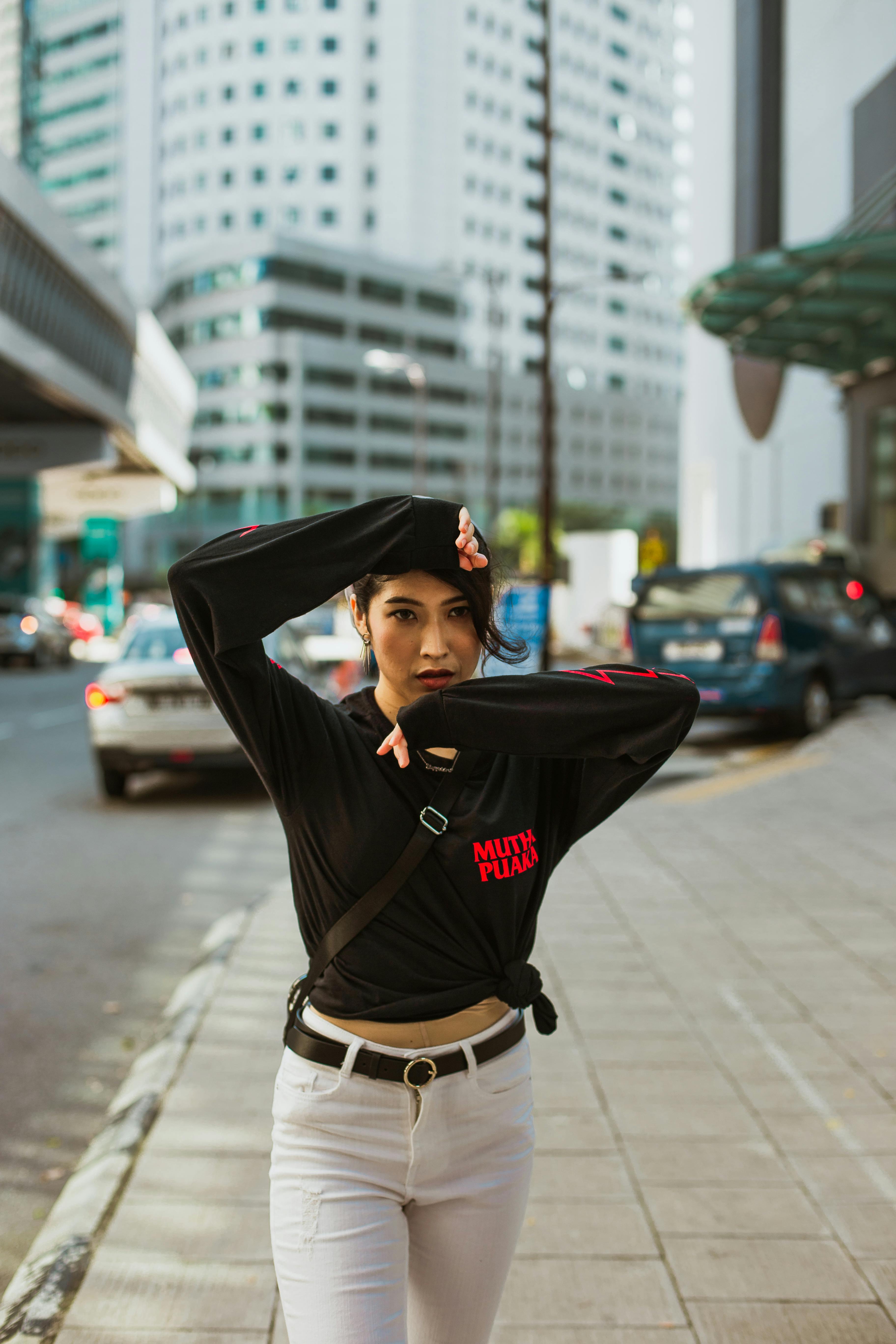 在市区户外，一位自信的女人身着黑色上衣摆着姿势