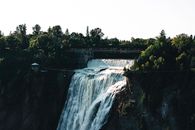 Stunning view of Montmorency Falls in Québec surrounded by lush greenery and a pedestrian bridge.