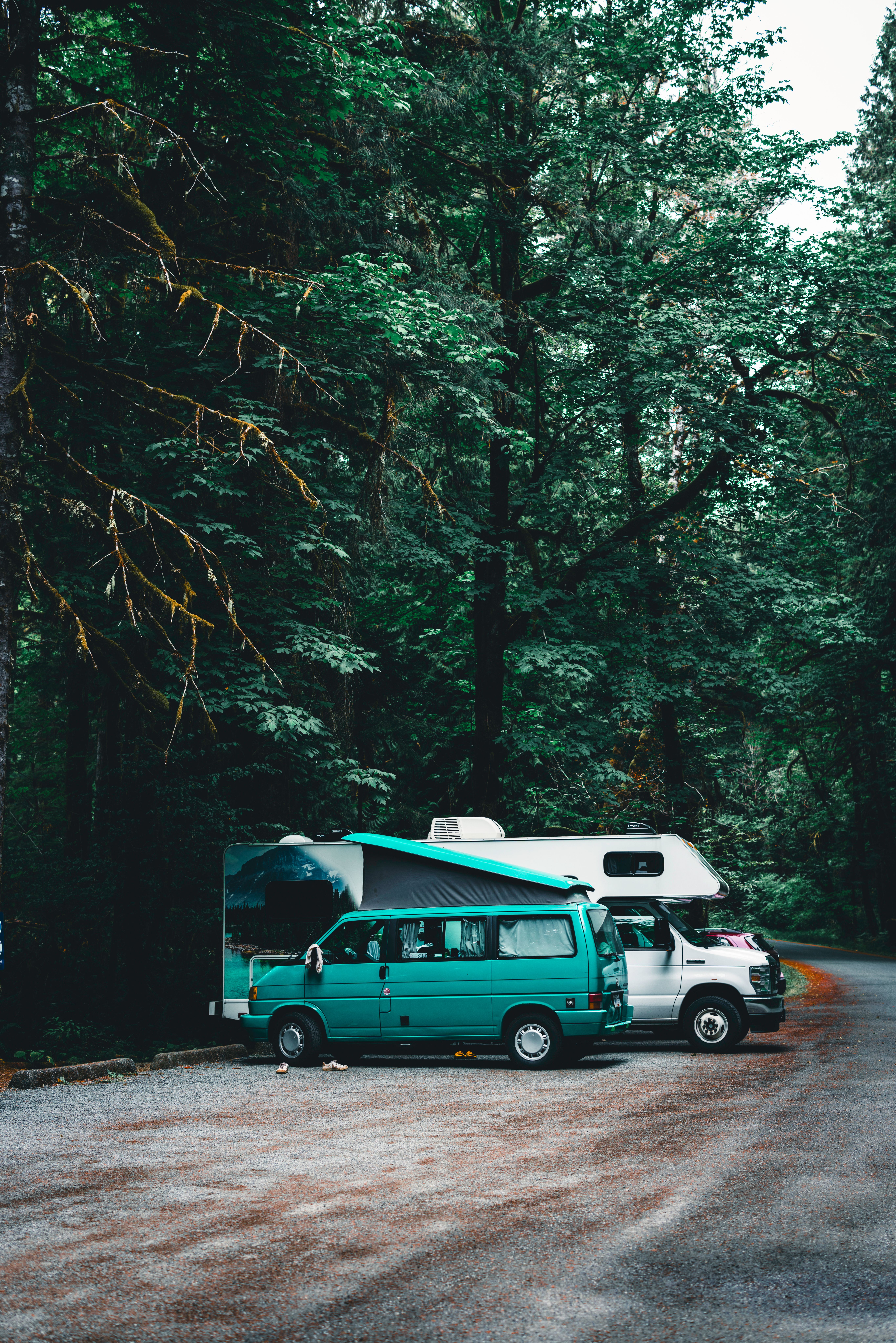 A scenic RV campsite near a forested lake at sunset with mountains in the distance