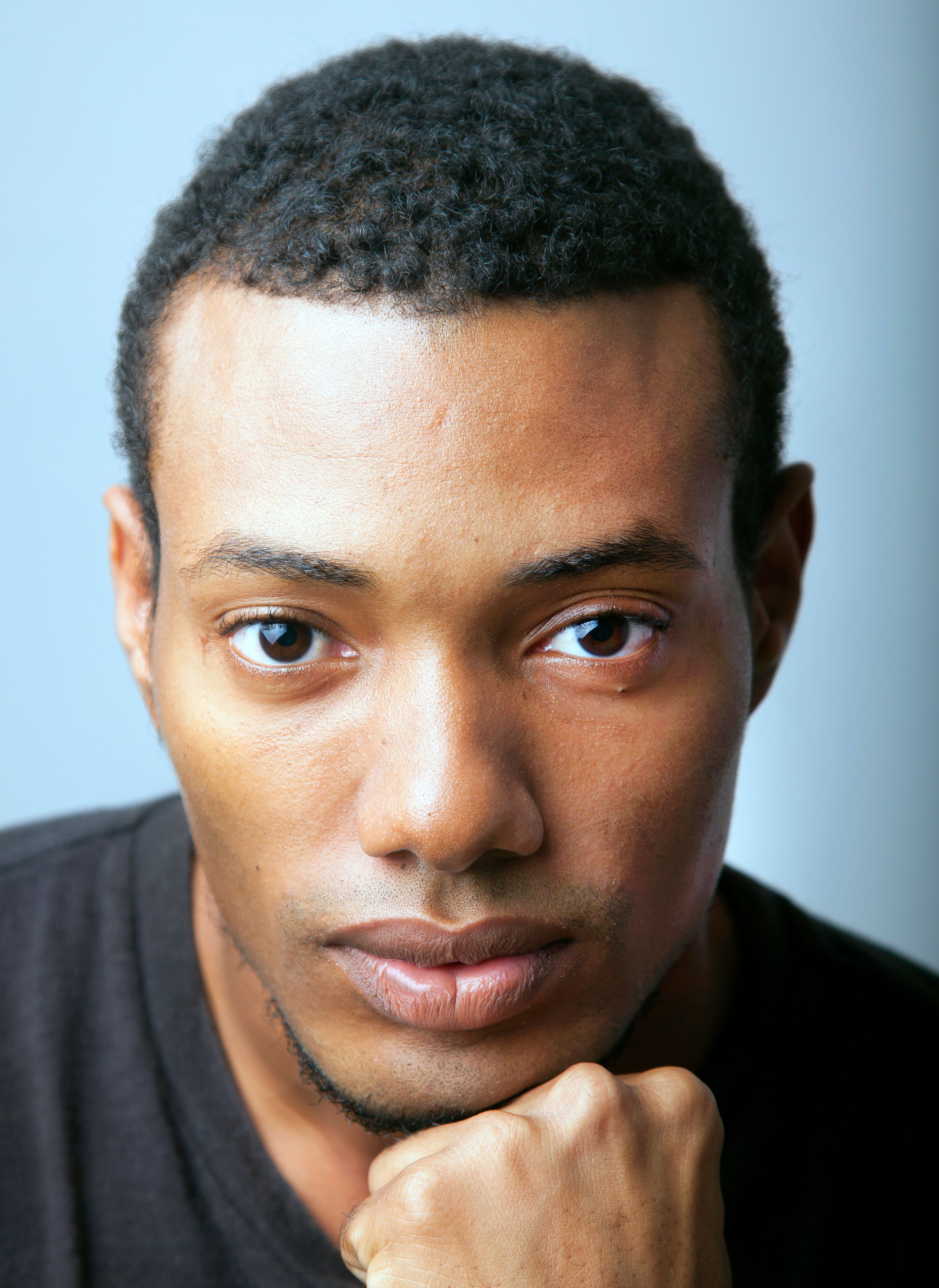 Close-up portrait of a young African American man posing in a studio setting.