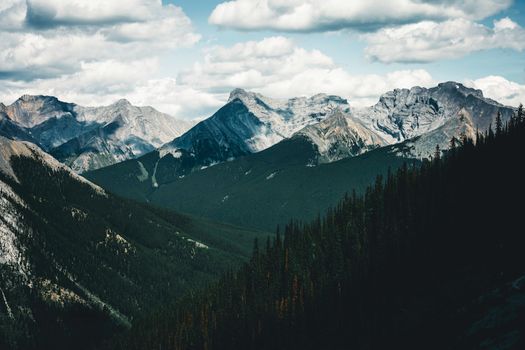 Dramatic mountain landscape in Banff National Park showcasing towering peaks and lush forests under a cloudy sky.