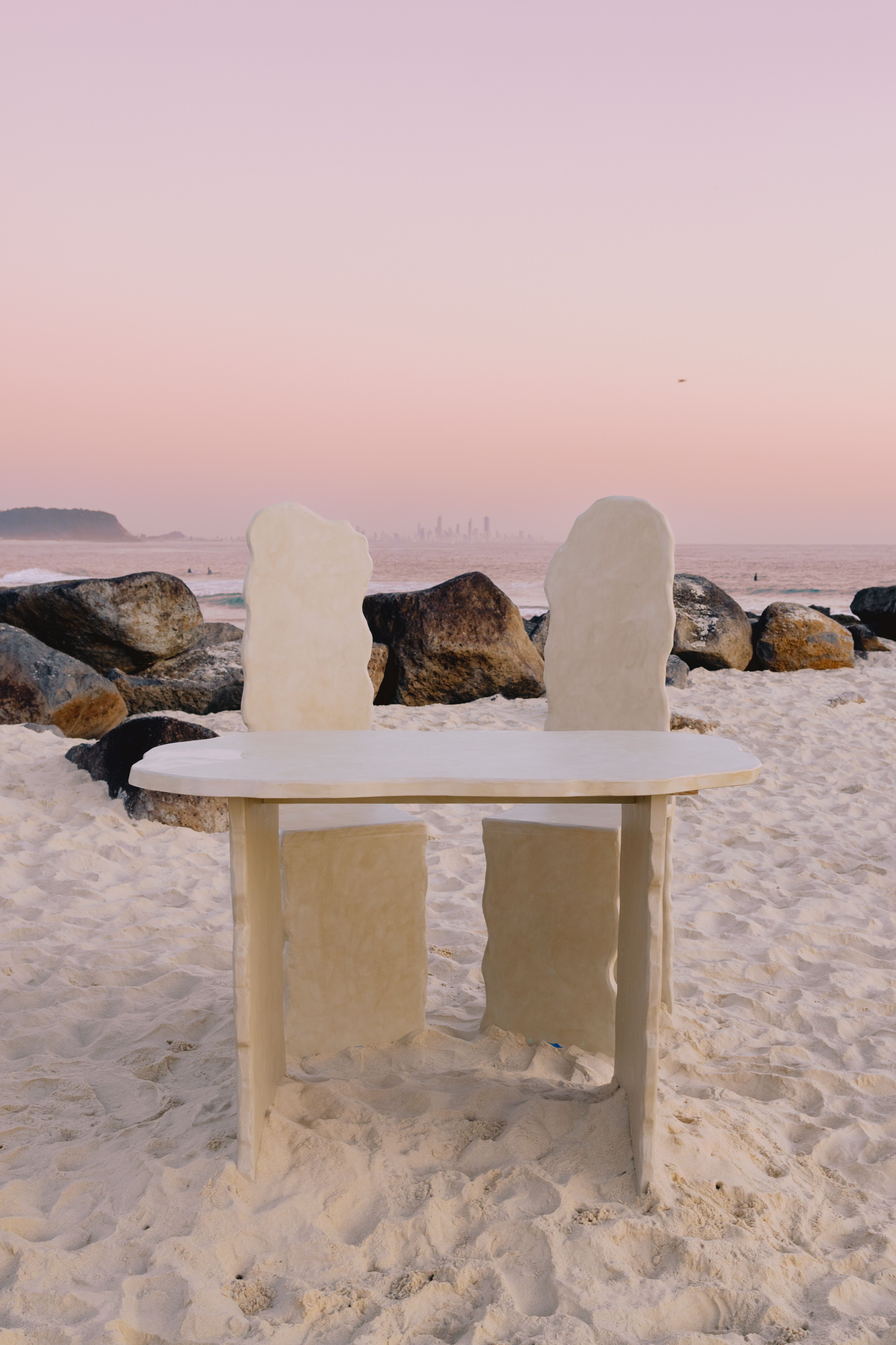 A stone table on Currumbin Beach with a pink sunset sky and ocean view in Queensland, Australia.