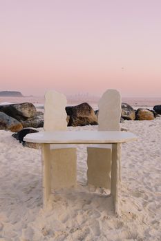 A stone table on Currumbin Beach with a pink sunset sky and ocean view in Queensland, Australia.