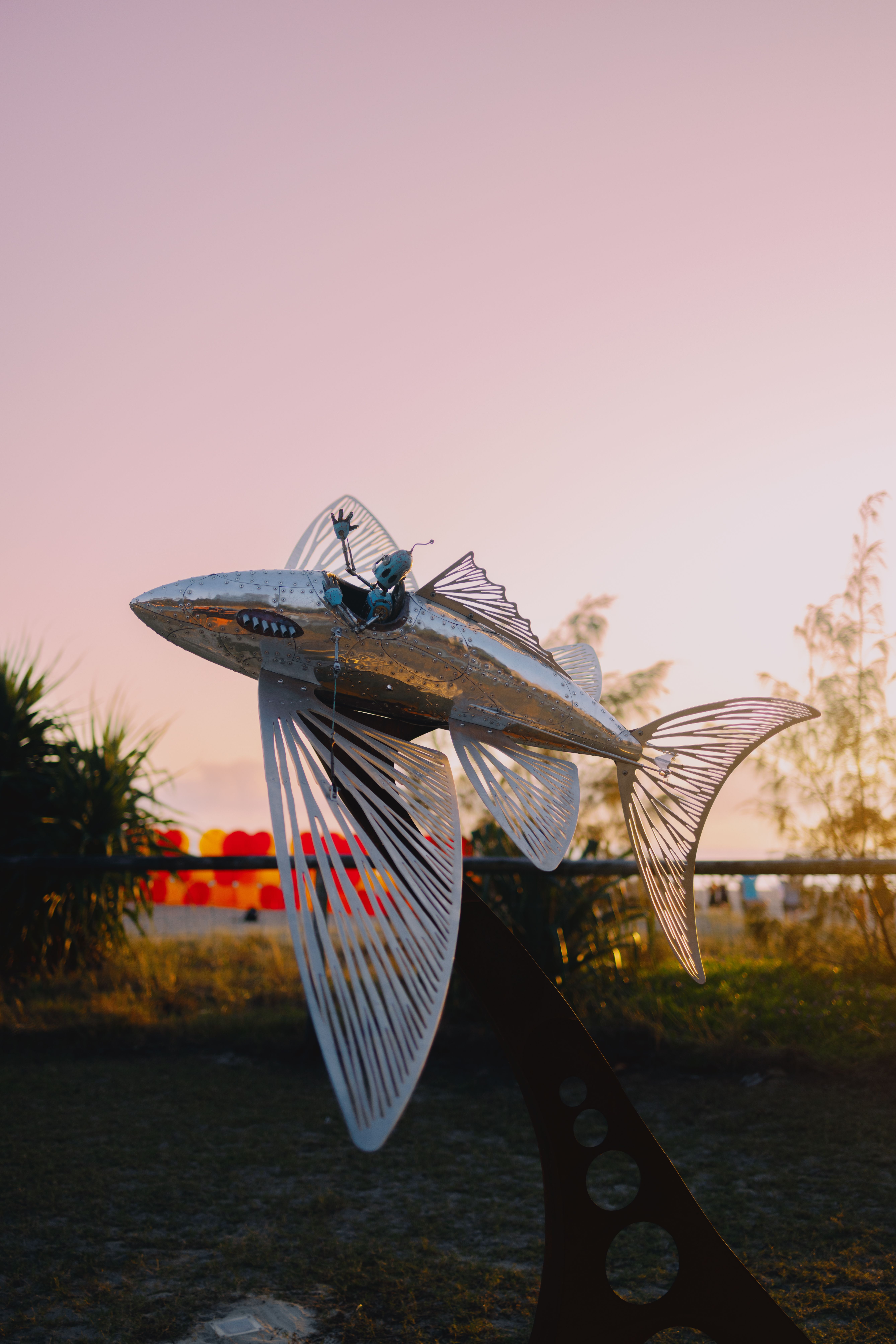 A striking fish sculpture with a pink sky backdrop at Currumbin Beach, Australia during sunset.
