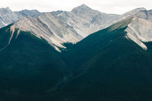 Aerial view of the stunning Rocky Mountains surrounded by lush forests in Jasper National Park, Canada.