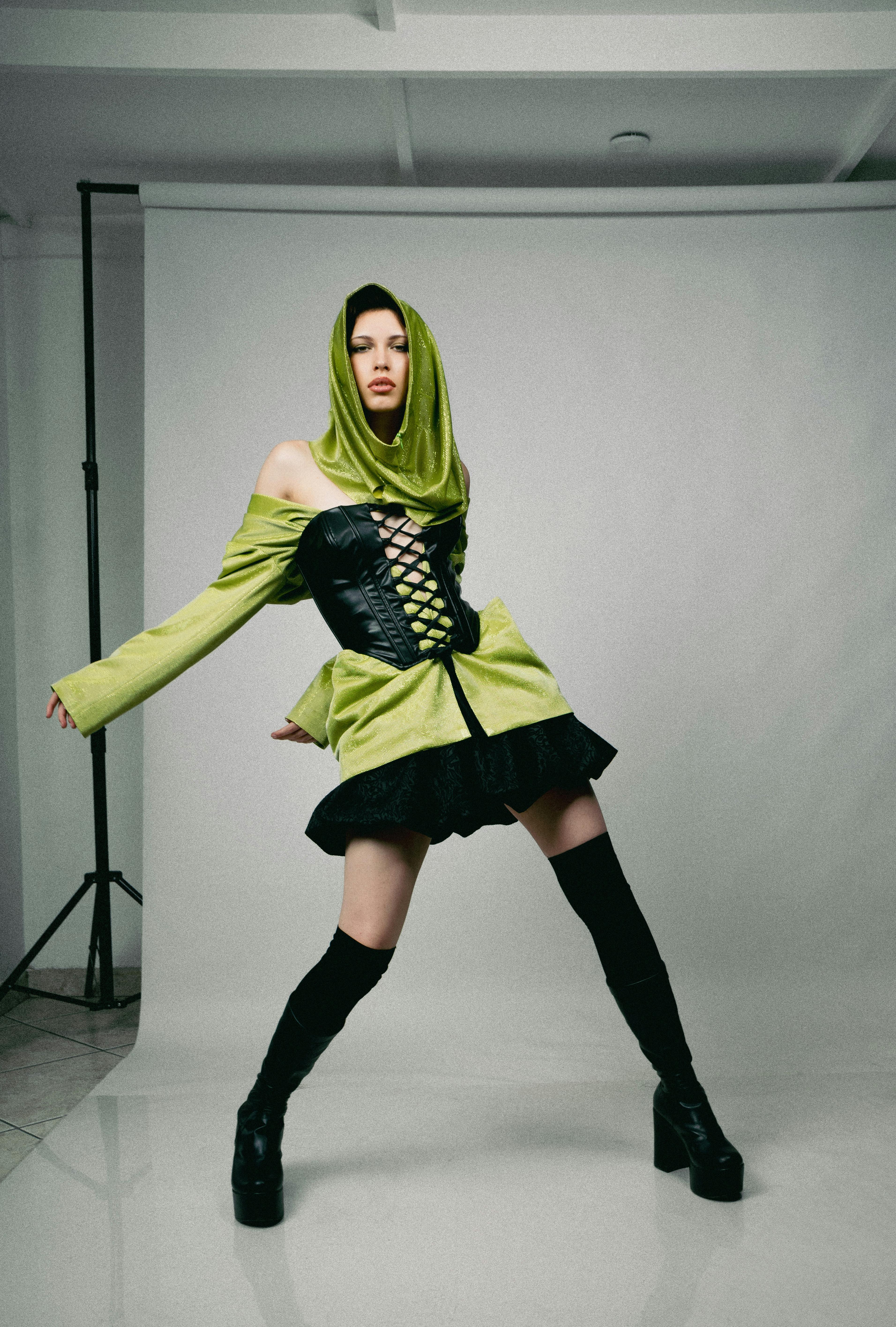 a woman in a green hoodie and black boots posing