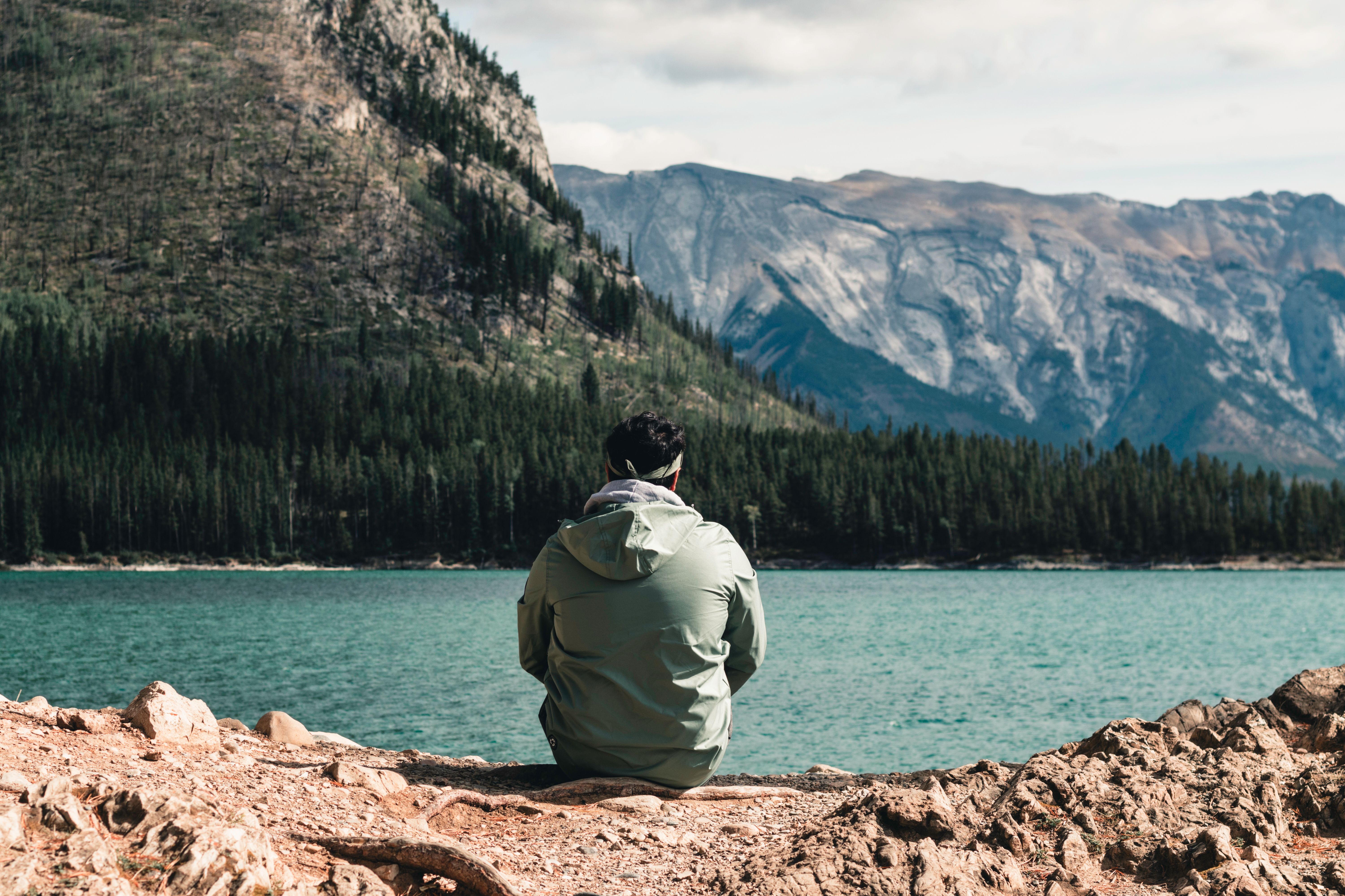 Explore tranquility with a lone hiker at a serene lake in Banff's majestic landscape