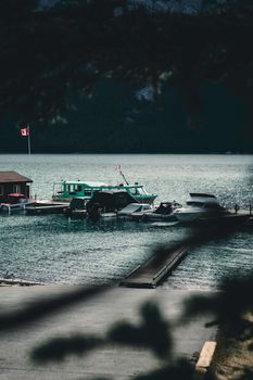 Serene scene of boats at a dock on Lake Minnewanka, Banff, surrounded by mountains and nature.