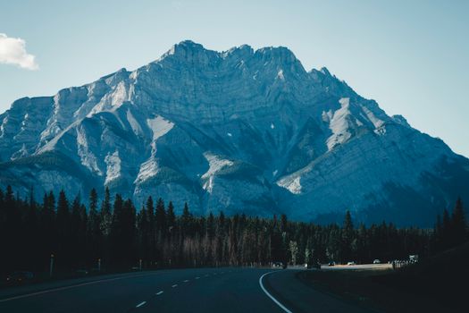 A picturesque view of the road winding towards the majestic Rocky Mountains in Banff, Canada.