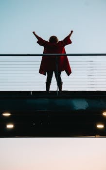 黄昏时，桥上有一个女人举起双臂庆祝的后视图