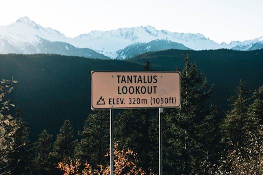 Stunning view of Tantalus Lookout with snow-capped mountains, forest, and signage in British Columbia, Canada.