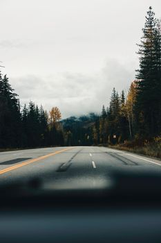 Peaceful mountain road in autumn, surrounded by misty forests and fall colors.