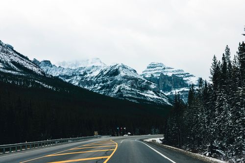 Free A picturesque winter scene in Kootenay National Park, featuring a highway leading to snow-capped mountains. Stock Photo