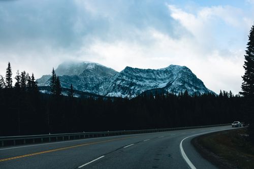 Free A scenic view of snow-capped mountains along a winding road in Kootenay Crossing, BC, Canada. Stock Photo