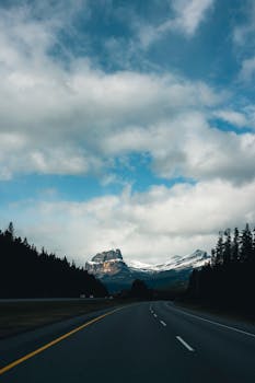 Explore the scenic beauty of Jasper National Park with this road leading to majestic mountains under a vast sky.