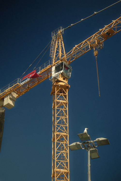 Free Bright yellow tower crane against a clear blue sky, symbolizing construction. Stock Photo