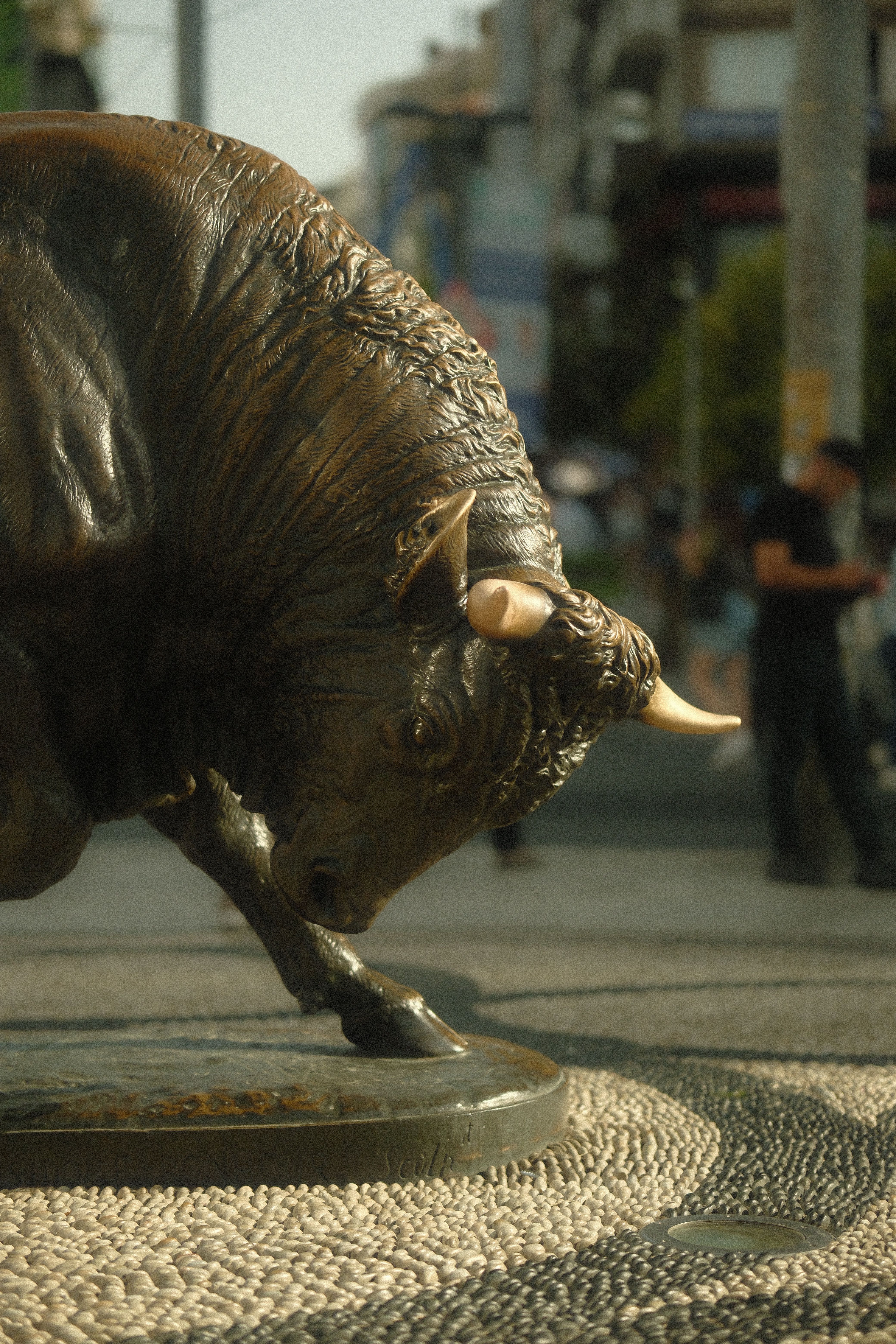 Powerful bronze bull statue on urban street capturing strength and tradition.