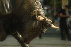 Powerful bronze bull statue on urban street capturing strength and tradition.